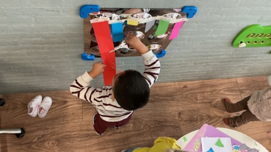 De peuters knippen en plakken de kleuren van het kleurenmonster. βοΈ